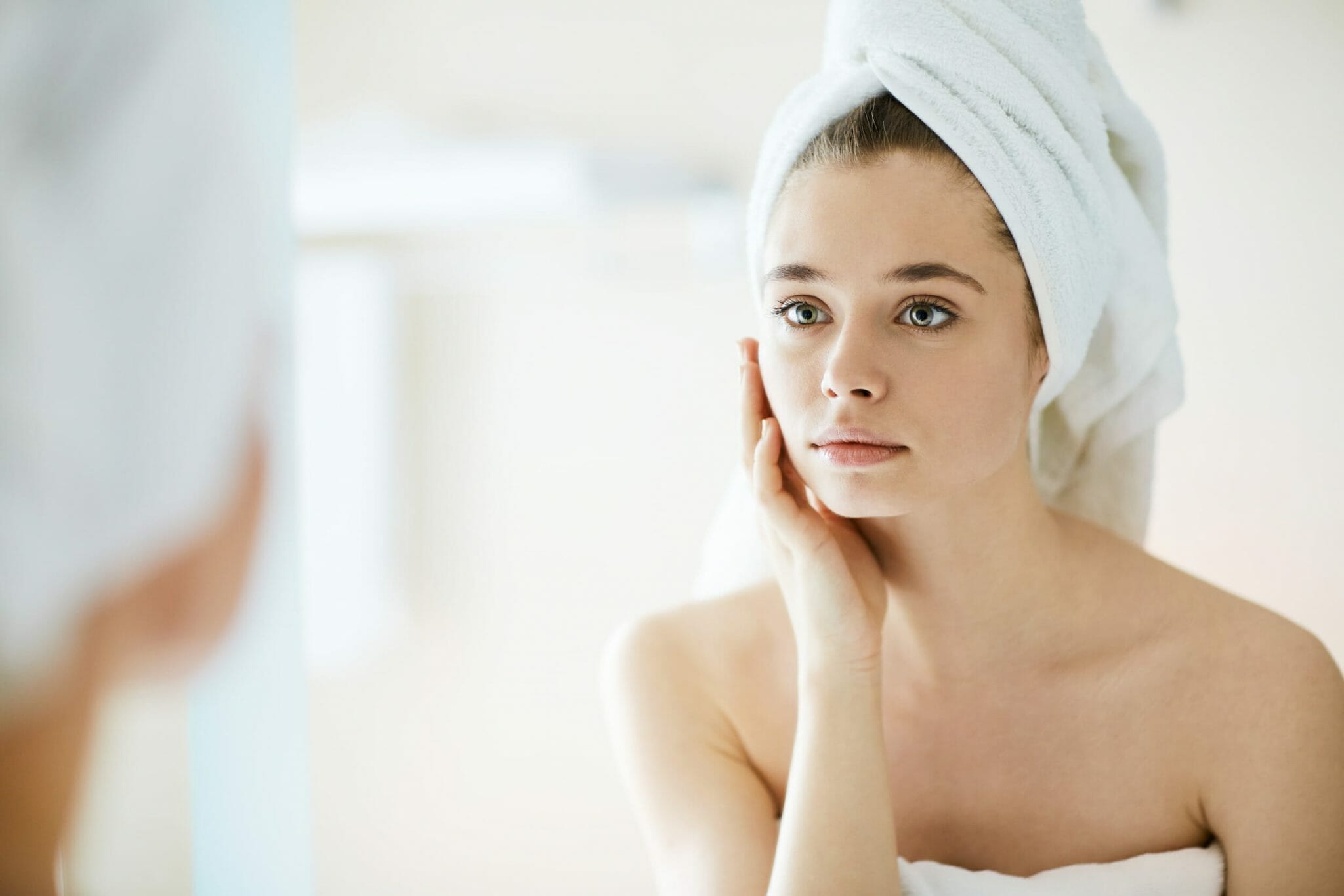 Young woman looking in mirror after bath or shower