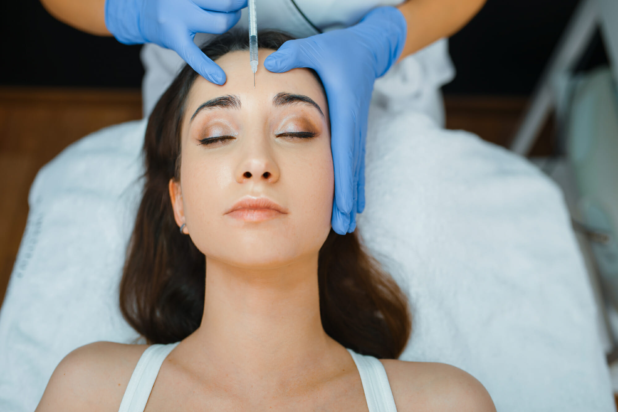 Cosmetician gives face botox injections to patient