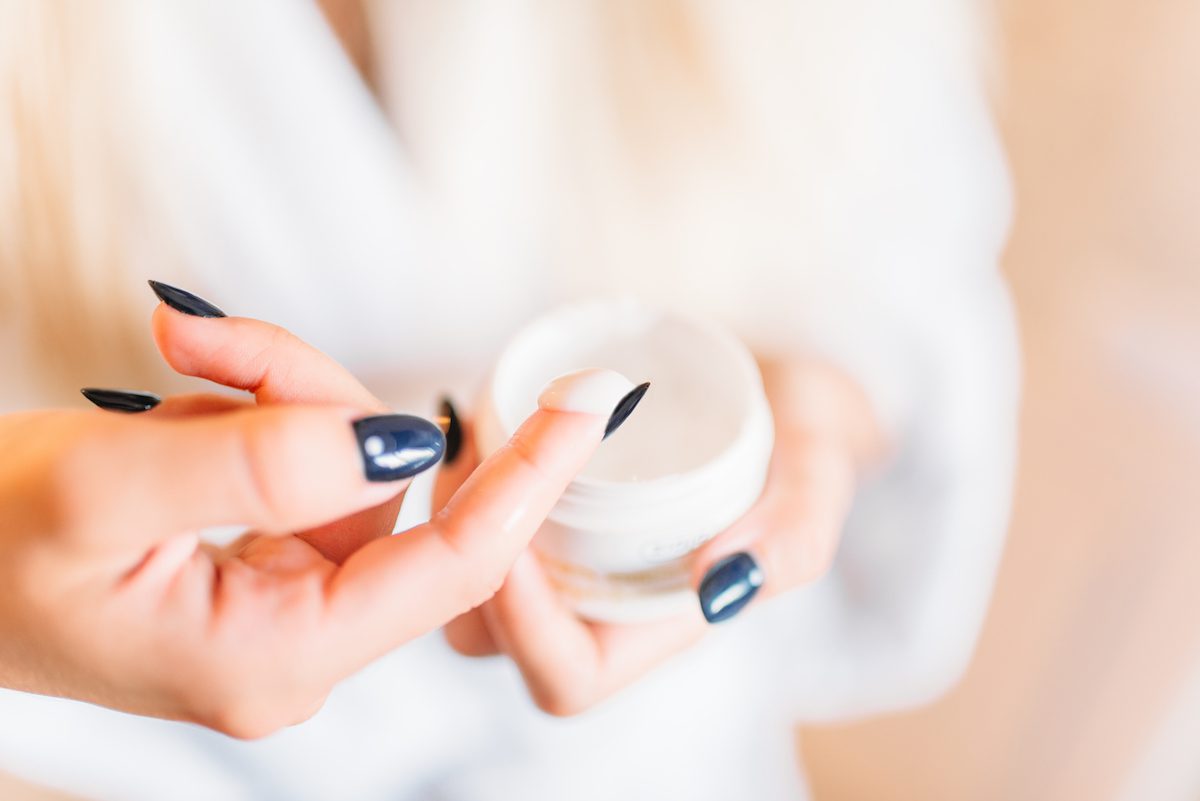 woman taking face cream on her finger