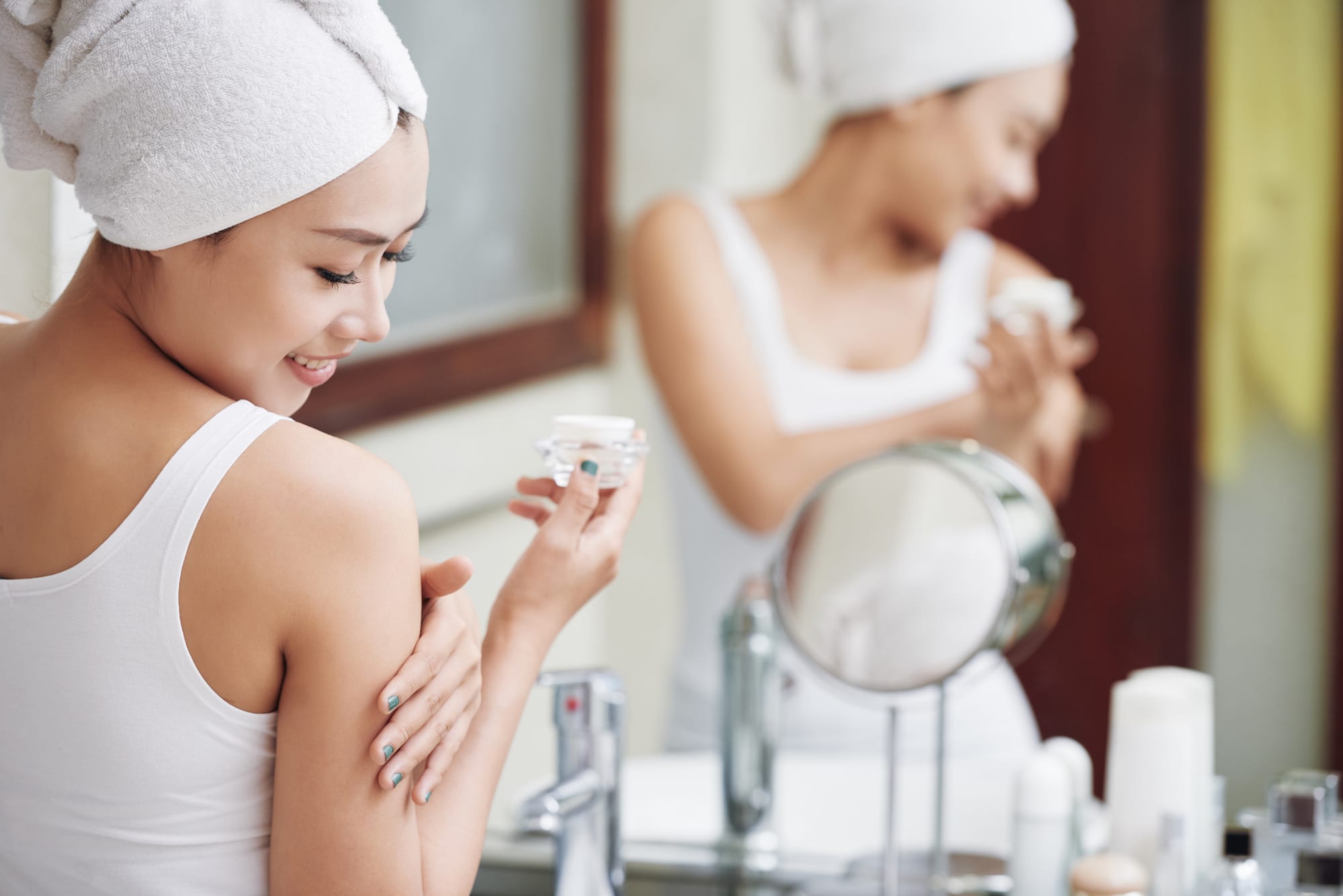 woman applying moisturizer to her shoulder