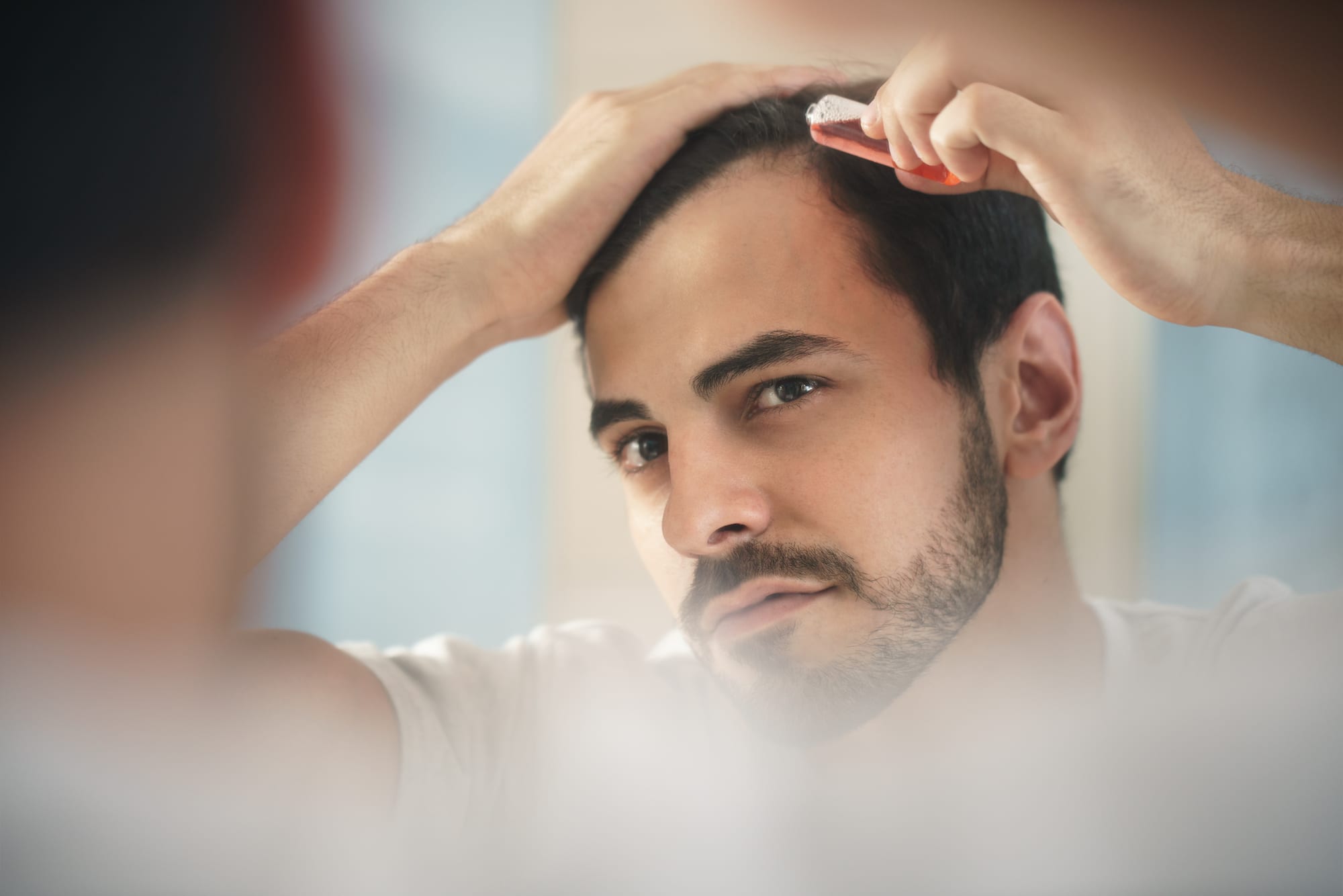 young man applies hair growth medication