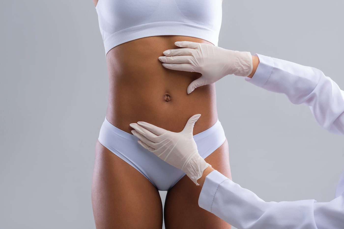 doctor pressing on woman's stomach after liposuction