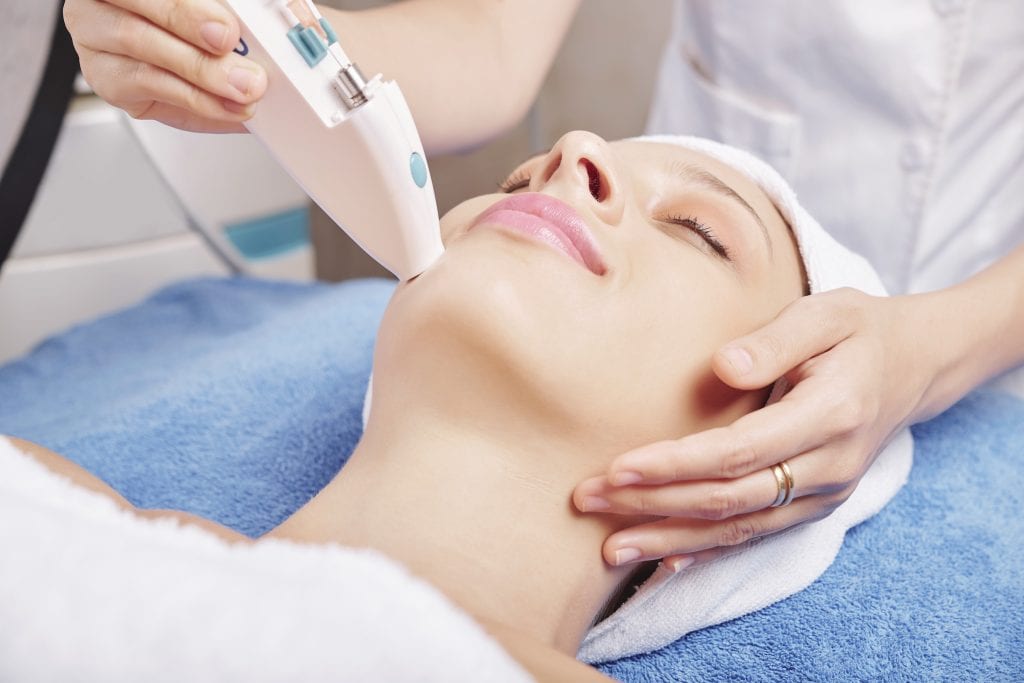 Young woman receiving a non-invasive facial procedure