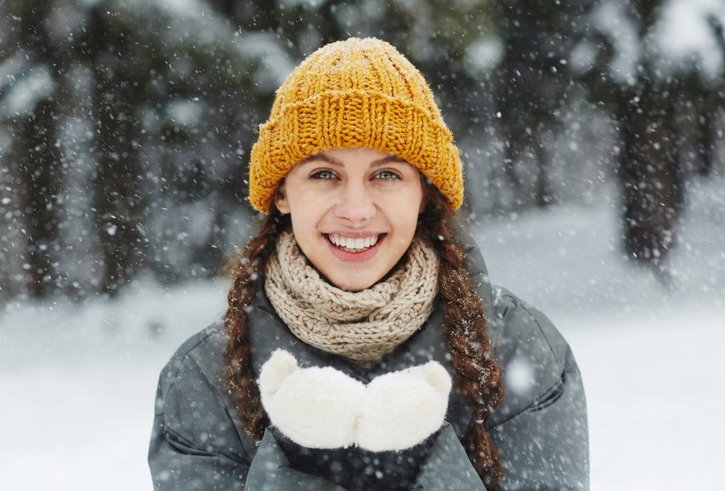 smiling young woman standing in the snow