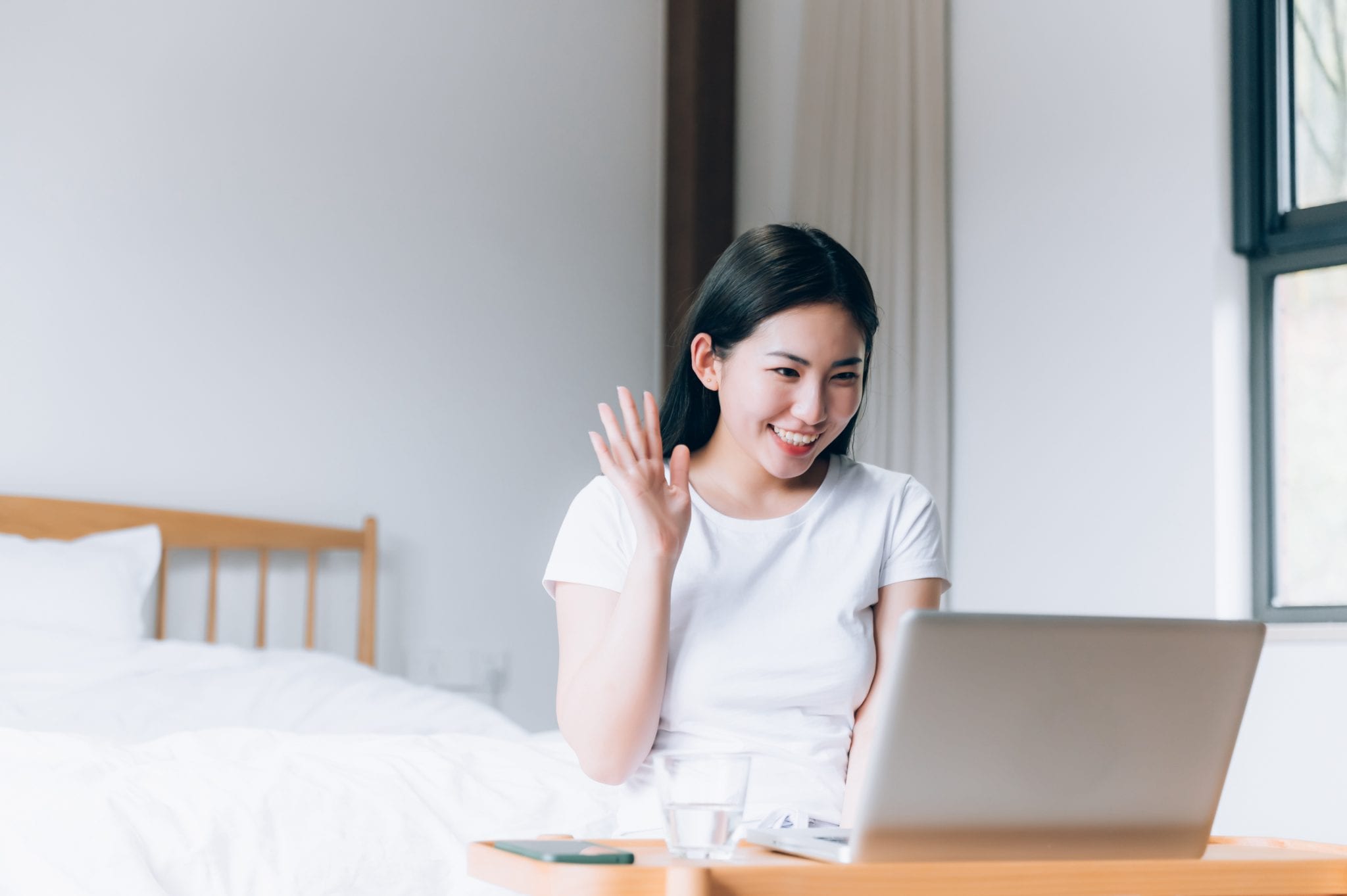 woman waving to someone on laptop