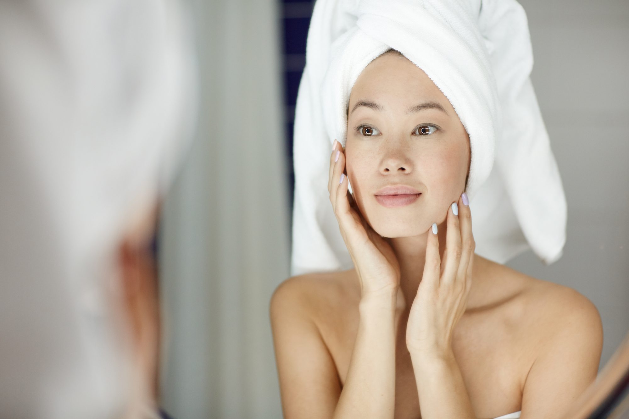 woman with towel on hair touching face