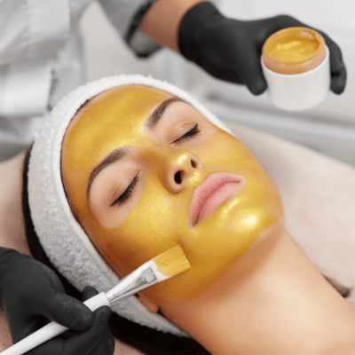 glow-mask woman receiving a golden peel mask